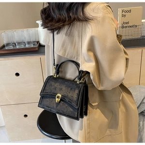 Détail d'un sac à main noir vintage avec un fermoir rotatif doré de haute qualité