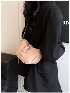 Detail of light pink patent leather shoulder bag with large metal buckle on black blazer
