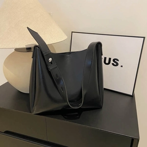 Sac seau minimaliste noir en similicuir avec large bandoulière pour un usage quotidien