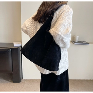 Detail shot of black matte suede tote bag worn over the shoulder by a model