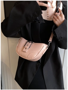 Détail du sac demi-lune en PU rose clair avec boucle argentée sur un blazer noir