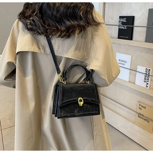 Détail du sac bandoulière en velours noir avec fermoir doré et design accordéon