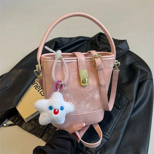 Pink suede-textured bucket bag with gold lock buckle and star plush accessory