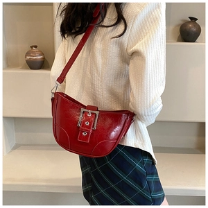Vue détaillée du sac croissant rouge en cuir verni brillant avec boucle en métal argenté