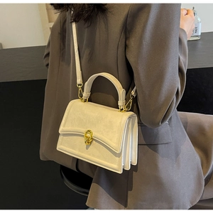 Détail du sac à main en cuir crème avec design à double rabat et fermoir doré rotatif