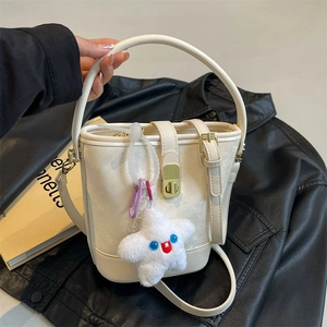 Chic cream white bucket bag with gold clasp and star charm on black leather background