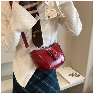 Détail du sac demi-lune rouge avec texture cuir ciré vintage et boucle métallique