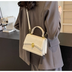 Détail du sac à main beige en cuir avec fermoir doré et bandoulière réglable