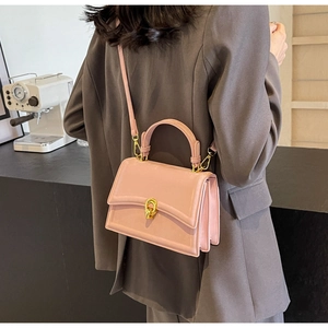 Petit sac à main rose avec boucle dorée en nœud porté dans un cadre de travail chic