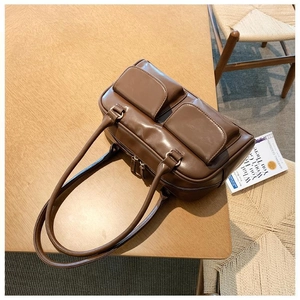 Detailed top view of a dark brown leather handbag with dual front pockets on wood