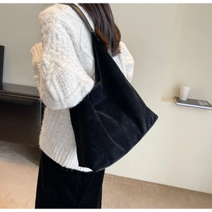 Macro shot of minimalist black suede hobo shoulder bag showing soft matte leather texture