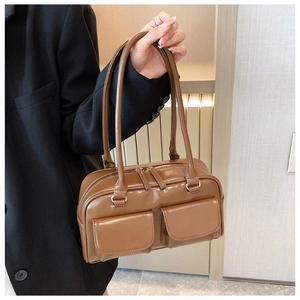 Detail of a brown PU leather baguette bag with dual front flap pockets and long straps