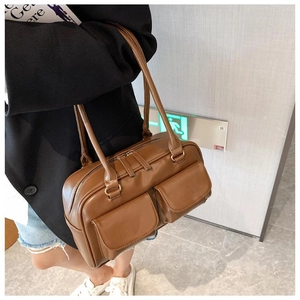 Detail view of brown shoulder bag featuring dual front pockets and zipper closure