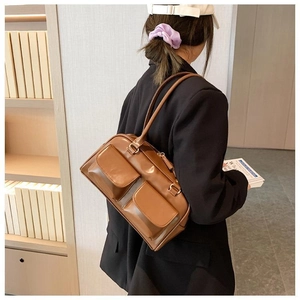 Detailed view of the brown PU leather shoulder bag with retro dual front pockets on a model
