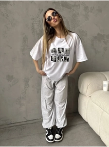Ensemble t-shirt blanc imprimé et pantalon large gris dans un studio minimaliste