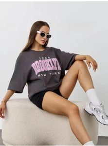 Detail view of the vintage pink Brooklyn graphic print on a dark gray cotton T-shirt