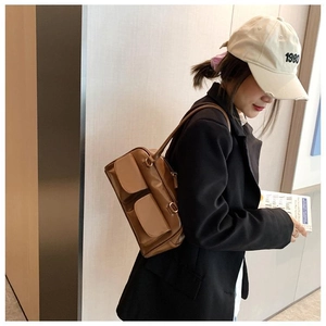 Brown vintage shoulder bag with double flap pockets on model in a stylish urban setting