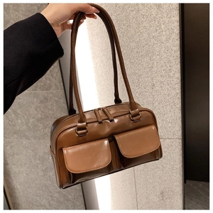 Detail of brown faux leather handbag showing two front flap pockets and dual zipper closures