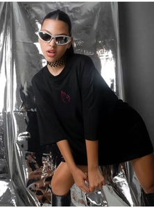 Macro shot of oversized black cotton T-shirt with pink flame print on Y2K silver background