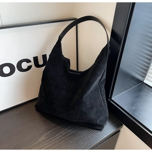 Detail of matte black suede tote bag with flat leather shoulder strap and soft texture
