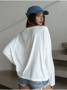 Back view of a white oversized cotton long sleeve t-shirt with dropped shoulders on a model