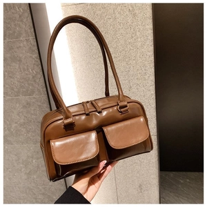 Detail of a brown PU leather tote bag featuring dual front pockets and long slim handles