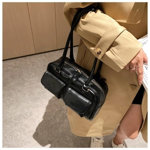 Detailed view of a black leather crossbody bag with dual front pockets worn by a model