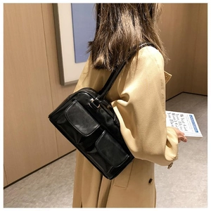 Detail of a black glossy shoulder bag with dual front pockets and sleek strap design