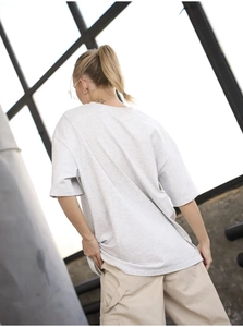 Back view of oversized light grey cotton t-shirt with industrial studio background