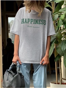 Detail of light gray cotton t-shirt with green HAPPINESS print and black leather bag