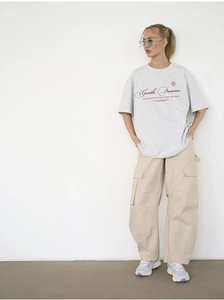 Detail of oversized cotton t-shirt with Gentle Dreams print and cargo pants styling