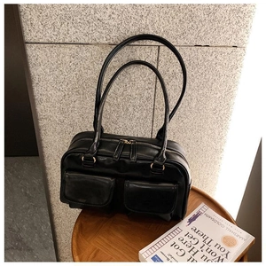 Macro shot of black leather handbag featuring dual front pockets and double zipper closure