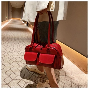 Detail of red faux leather handbag with front pockets and long shoulder straps