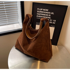 Detail view of the soft matte suede texture and stitching on this dark brown tote bag