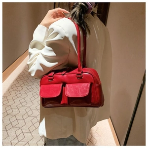 Close-up of vibrant red leather shoulder bag with double pockets and white suit outfit