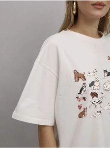 Détail d'un t-shirt blanc en coton avec des motifs de chiens et une lettre rouge brodée