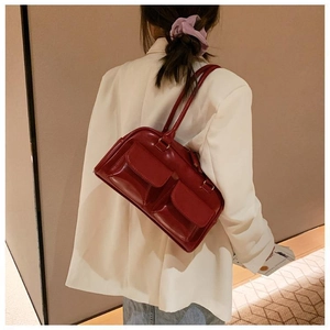 Detail of a dark red rectangular shoulder bag with dual front flap pockets on white blazer