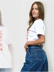 Detail of white polka dot t-shirt featuring pink geometric pattern and denim styling