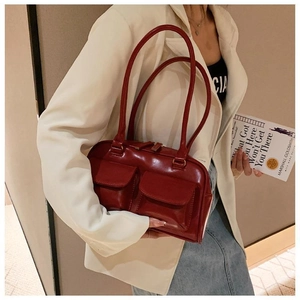 Macro shot of red glossy boston bag with dual front flap pockets on a model