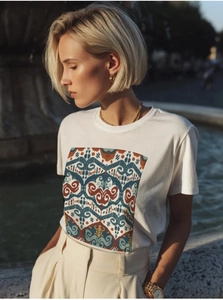 Detail of white cotton T-shirt featuring a colorful geometric ethnic print on the chest