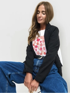 Detail of a white round neck T-shirt with orange abstract art and a chic black blazer