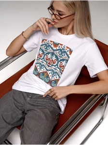 Detailed view of women's white cotton T-shirt featuring a colorful geometric ethnic print