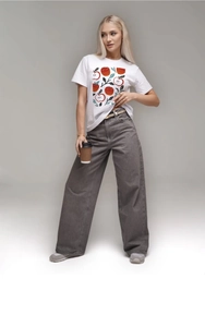 Dettaglio maglietta in cotone bianco con stampa mela rossa e pantaloni larghi in denim