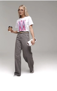 Détail d'un t-shirt en coton blanc avec motif en V et jean large décontracté