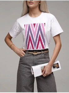 Détail de l'imprimé géométrique coloré sur un t-shirt en coton blanc et une ceinture chic