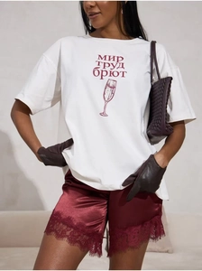 Detail eines weißen Baumwoll-T-Shirts mit rotem Grafikdruck und stilvollen Accessoires