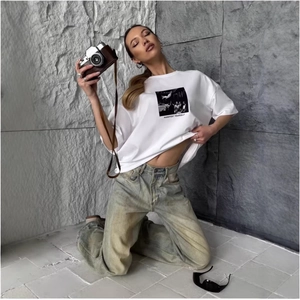 White drop shoulder cotton t-shirt with manifest print and light wash denim jeans