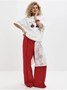 Détail du t-shirt blanc en coton avec imprimé matriochka et pantalon rouge en dentelle