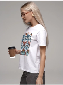 Detail of colorful geometric tribal print on white 100% cotton crewneck summer T-shirt
