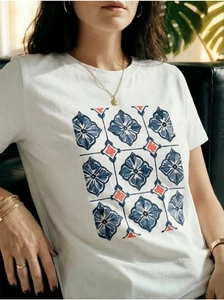 Detailed close-up of white cotton T-shirt featuring vintage geometric floral print and neck detail